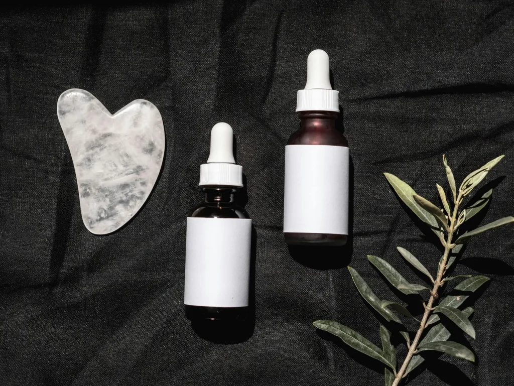 Rose water in a dropper bottle , next to gua sha.